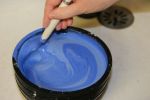 Mélange à la cuillère du plâtre liquide avec un pigment bleu